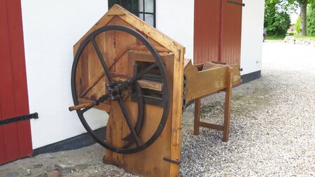 Hand operated wooden straw cutter on display in southern Danish farm yard
