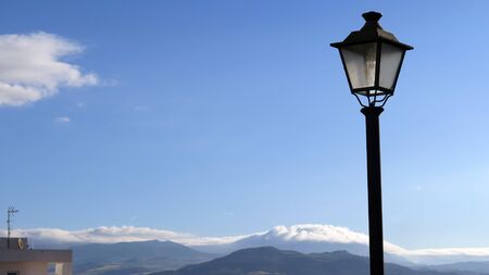 Lantern seen against mountains with low white clouds in Andalusian village sunshineの写真素材