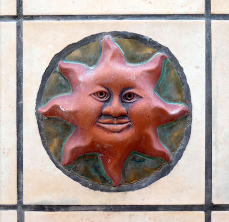 Decorative tile in form of smiling face of sunの写真素材