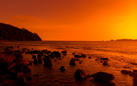 Ocean orange sunset landscape with rocks in silhouetteの写真素材