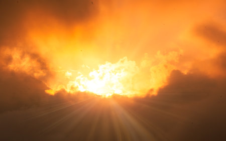 Sunset with sunbeams and clouds in the sky background.