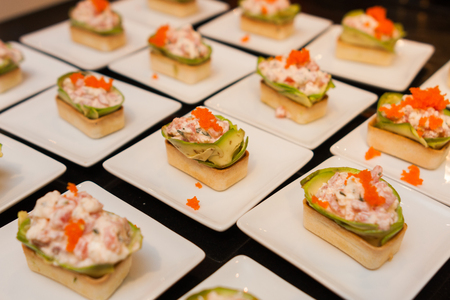delicious gourmet canape starters with avocado and caviar on white platesの写真素材