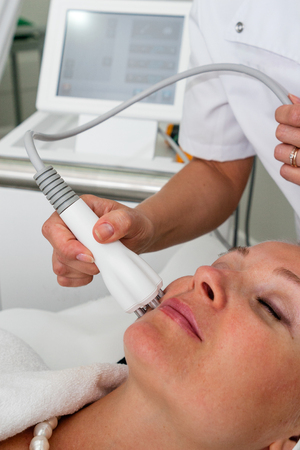 TENERIFE, Spain, July 2014: Aesthetic medicine and cosmetology. Closeup portrait of female face with closed eyes getting ultrasonic peeling in a beauty clinic on Adeje Sur.のeditorial素材