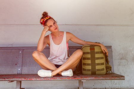 oung sexy woman backpacker sitting on bench on railway station.Travel concept.の写真素材