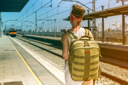 Young sexy woman backpacker waiting for train on platform on railway stationの写真素材
