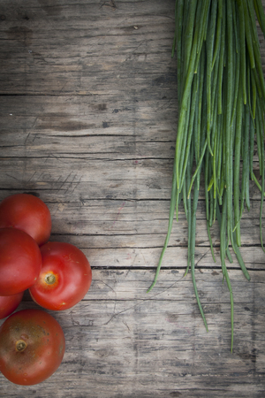 fresh tomatoes and onion on wooden plateの写真素材