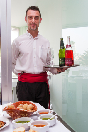 Tenerife, Spain, January 2015: waiter carrying a tray of wine on grand opening new shopping centre in Adeje Surのeditorial素材