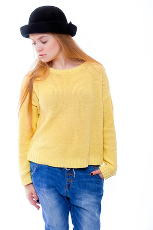 Teenage girl or young woman in yellow sweater and black hat looks surprisedの写真素材