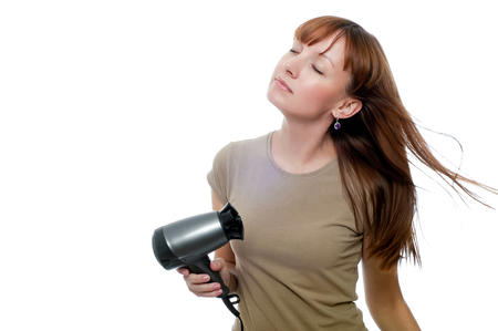 Redhead woman using hairdryer isolated on whiteの写真素材