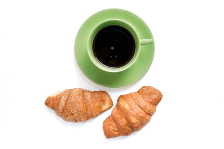 Two croissants on white plate and black coffee in green cup, top view. Sweat baked dessert in a dish.の写真素材