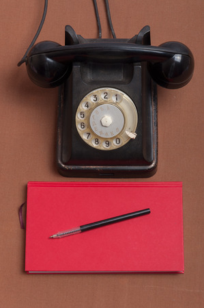 Retro style black russian dial telephone and red notebookの写真素材