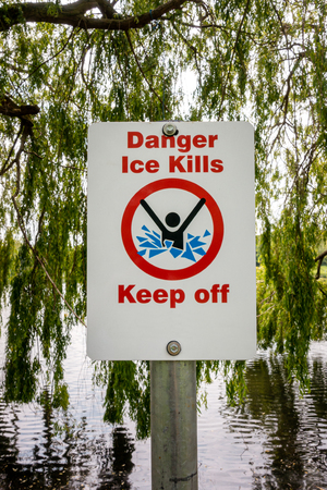 Danger ice kills keep off sign post on the bank of a small lakeの写真素材