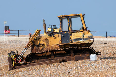Old yellow rusting bulldozer on a seafront beach on a dull day