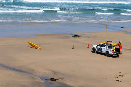 Royal National Lifeboat Institution Lifeguard vehicle and Paddleboard on seashore beachの写真素材