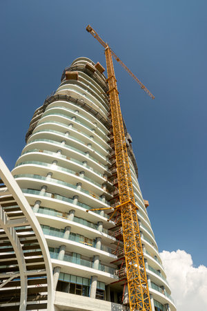 Construction of a high-rise building with a crane on a background of blue skyの写真素材