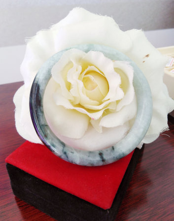 A beautiful jade bangle with white rose presented, showcasing elegance and charm. Perfect for highlighting beauty in various designs.の写真素材