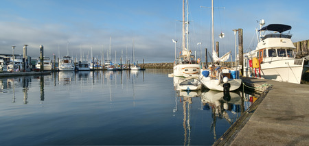 Pleasure boats in marina reflected in calm blue water of early morning at Des Moines, Washingtonのeditorial素材