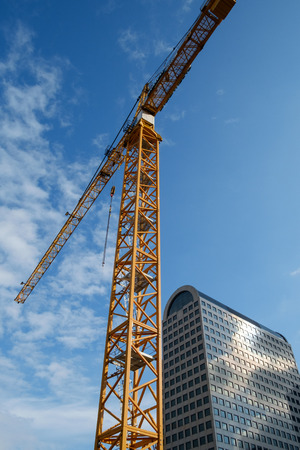 Seattle, WA, USA July 17, 2016: Yellow construction crane rising into blue sky with highrise office building in backgroundのeditorial素材