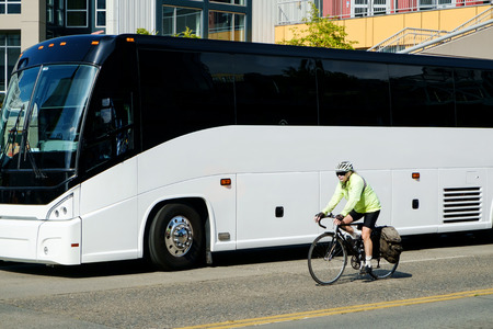 Large luxury tour bus and cyclist on city streetのeditorial素材