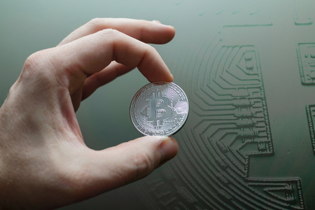 Businessman hand holding glowing bitcoin sign on interior background. Double exposure