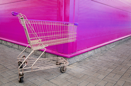 Empty shopping cart parking on violet or pink background with copyspace. retail storeの写真素材