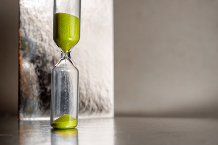 Modern beautiful yellow hourglass with bright background for copy space. Hourglass time passing concept for business deadline, urgency and running out of timeの写真素材
