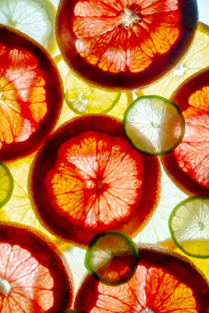 mixed colorful sliced fruits orange, lime, grapefruit, lemon. background back lightedの写真素材