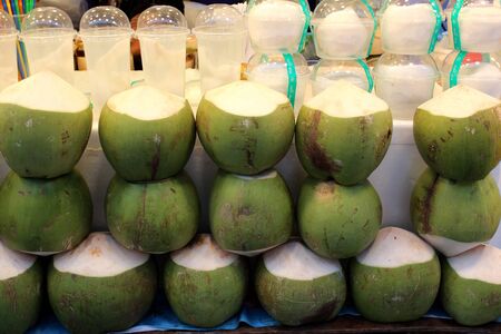 Coconuts and coconut juice in clear plastic glasses for sale at a market in Bangkok, Thailandの写真素材
