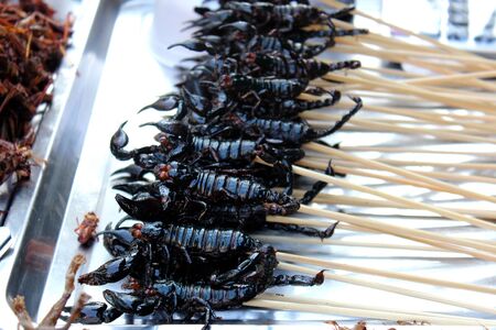 Fried scorpions on skewers placed on the stall for sale at a market in Bangkok, Thailandの写真素材