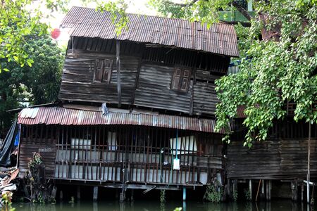 A dilapidated wooden house by the canal in Bangkok, Thailandの写真素材