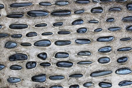 Black pebbles embedded in the concrete as a backgroung