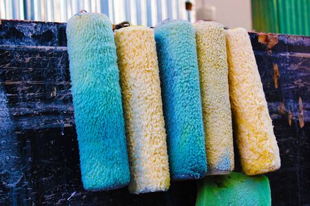 Five used paint rollers hanging for future useの写真素材