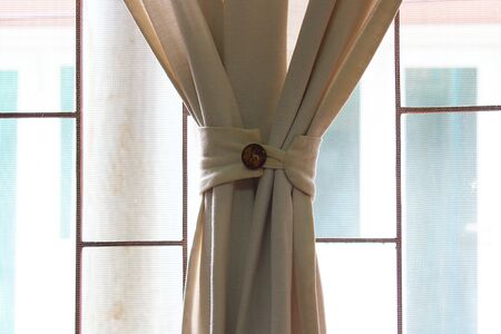Window curtain that is tied during the day timeの写真素材