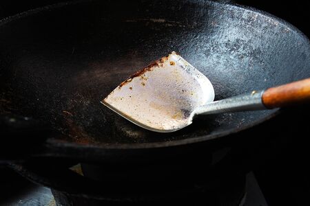 Old iron pan which has been used for a long time until black and spade of frying pan with food scraps stuckの写真素材