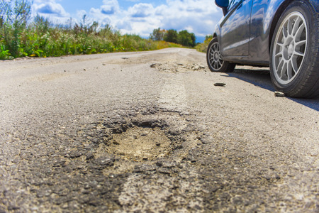 bad road cracked and damaged. car in blurred backgroundの写真素材