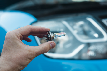 man hand changing light bulb on car headlightの写真素材