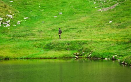 man walking in nature. green meadow and lakeの写真素材