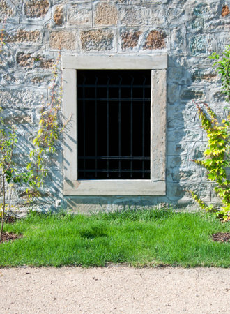 Barred window in old stone wall の写真素材