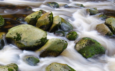 Mountain river waterfall between stones and autumn vegetation.の写真素材