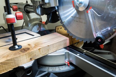 Closeup of mature sawing lumber with sliding compound miter saw の写真素材