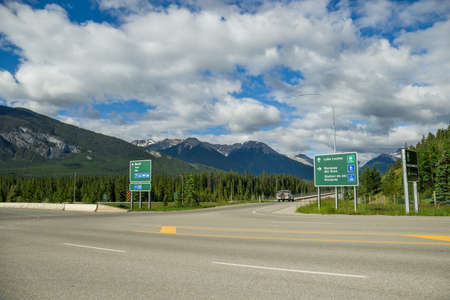Mountain Highway road with car. Crossroad and sign. Summer time. Banff, Alberta, Canadaの写真素材