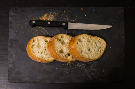 Slices of bread and a knife on a black background.の写真素材