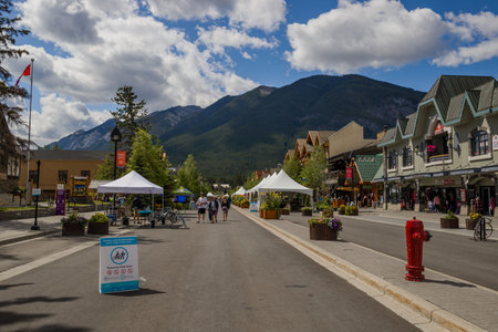 Banff downtown life - cars parked near houses, cafes, people walking on the streets. Summer day in a mountain village. Banff, Alberta, Canadaのeditorial素材