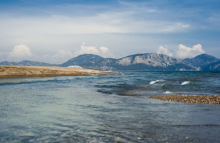 A view of mountains with forest meeting the sea on the coast. Wild beach seashore in daytime. Wild tourismの写真素材
