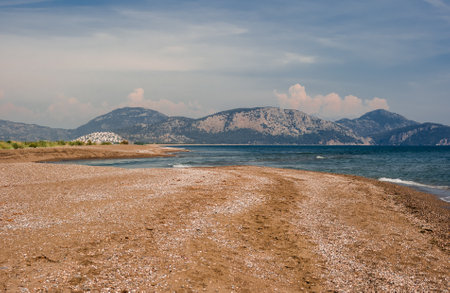 beautiful sandy beach on the Sea coast. A view of mountains with forest meeting the sea on the coast. Wild beach seashore in daytime. Wild tourismの写真素材