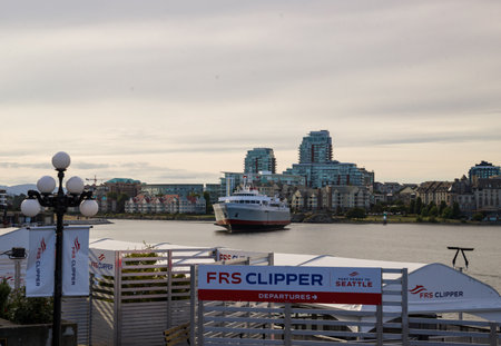 A view of the waterfront in Victoria, Canada, with a large passenger ferry arriving from Seattle against the backdrop of modern buildings on the waterfront.の写真素材