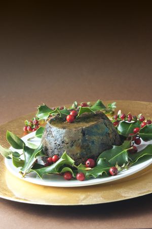 christmas pudding with holly and red berries on brown backgroundの写真素材