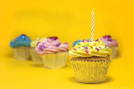 cupcakes shot on a yellow background with one candleの写真素材