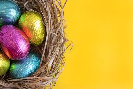 chocolate easter eggs in a nest on yellow background