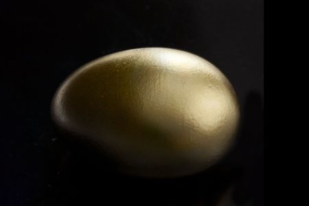 golden egg on a black background with dark shadowingの写真素材